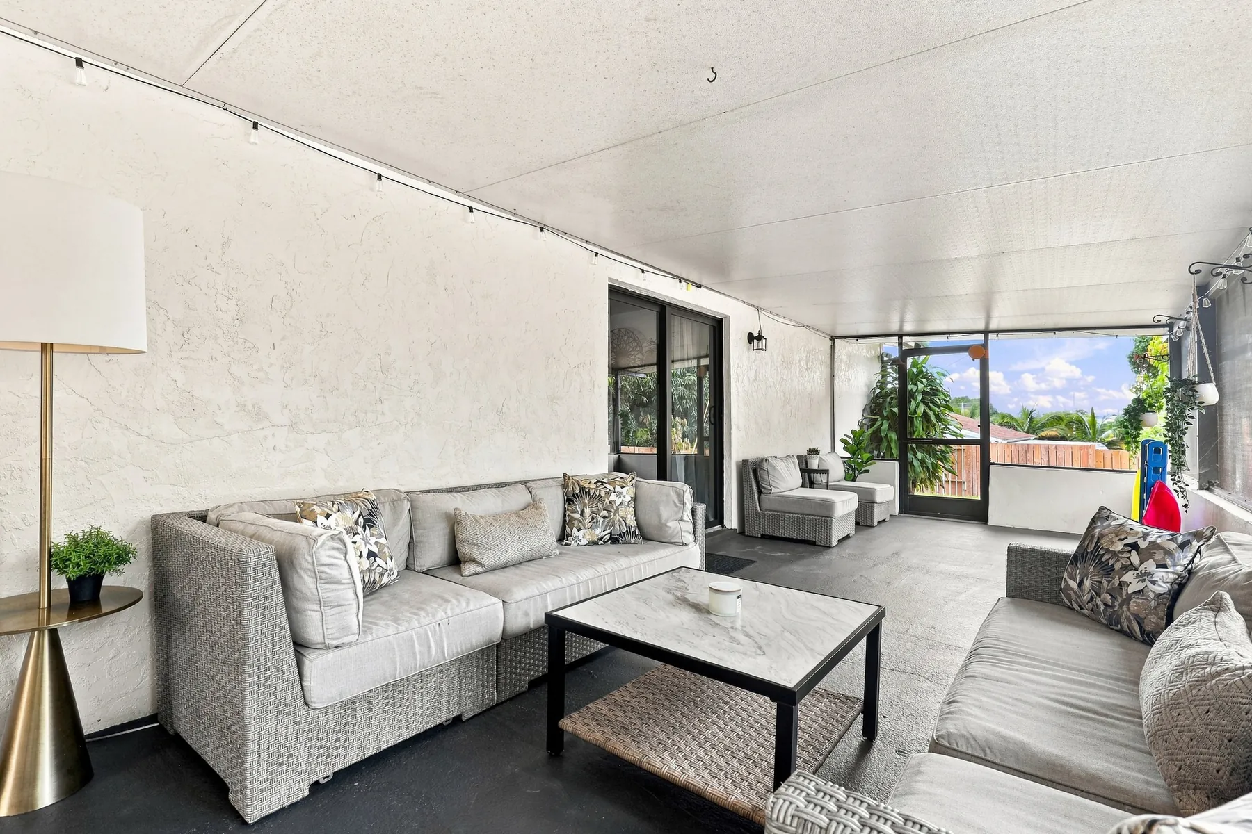 Bright screened lanai with sofas and a coffee table, opening onto the garden